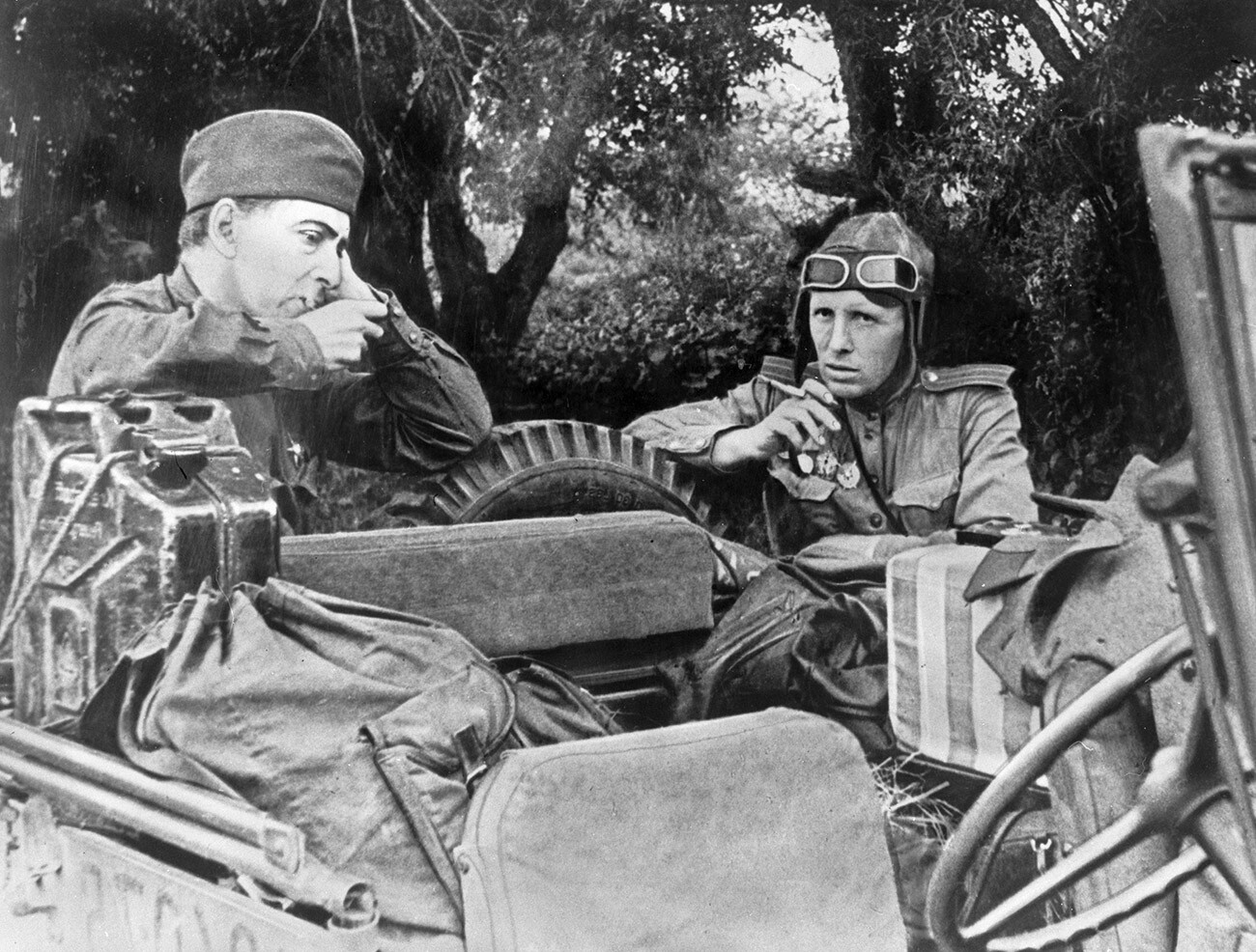 Correspondentes de guerra durante pausa para um cigarro na frente, perto de um veículo Willys MB