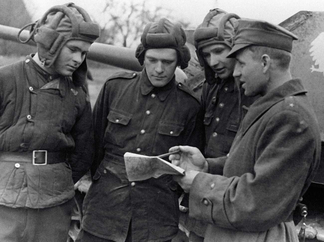 A podporuchik (second lieutenant) of the Polish Army (right) sets a combat mission to the crew of a self-propelled gun.