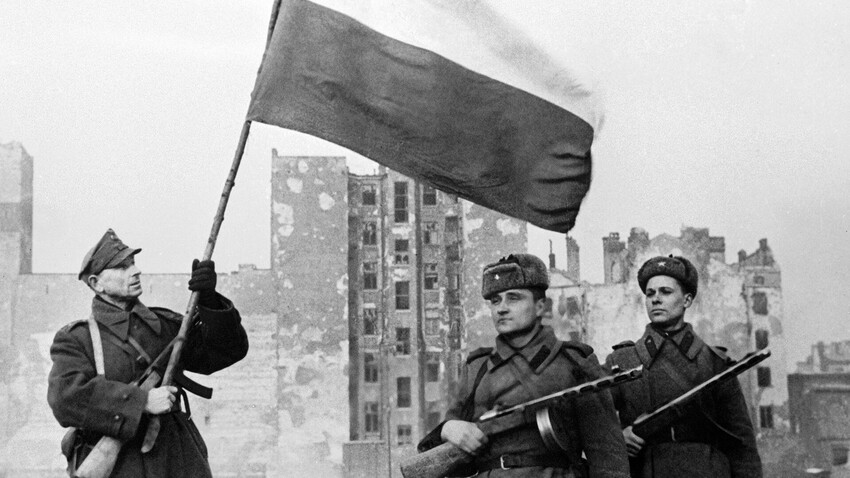 Soldados del 1er Ejército Polaco (izquierda) y del Ejército Rojo (derecha) izan la bandera nacional polaca sobre la Varsovia liberada.