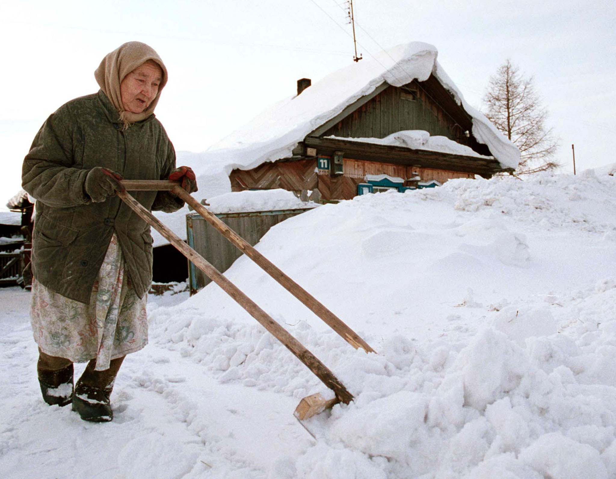 Seorang wanita tua membersihkan salju di sebuah perkampungan di luar kota Kemerovi, Siberia.