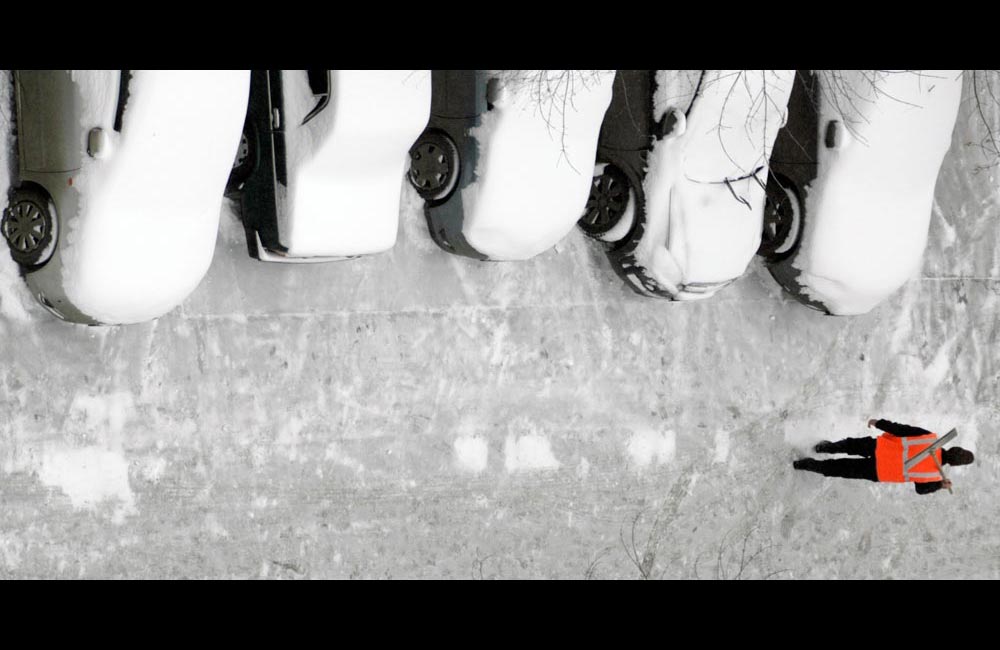 9/21. Радник комуналне службе носи лопату за чишћење снега пролазећи поред аутомобила прекривених снегом у Москви.