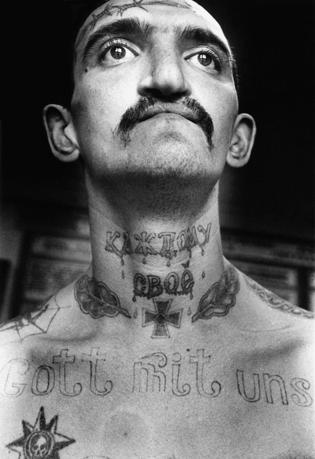 This inmate was convicted for drug related crimes. 'Gott mit uns': 'God with us' was a rallying cry of both the Russian empire and the Third Reich. The Nazi Iron Cross expresses ‘I don’t care about anybody’. This symbol of aggression and insubordination is often tattooed on the chest tattooed as if hung on a chain. The barbed wore on the forehead denotes that the bearer ‘will never be corrected’.