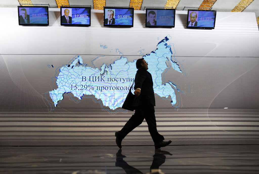 A man walks past a map of Russia and portraits of presidential candidates, from left: Vladimir Zhirinovsky, Gennady Zyuganov, Sergei Mironov, Mikhail Prokhorov and Vladimir Putin at the Putin&#039;s headquarters in Moscow, Russia, March 4, 2012. Prime Minister Vladimir Putin won Russia&#039;s presidential election on Sunday, according to exit polls cited by state television, but the vote was tainted by widespread violations claimed by the opposition and independent observers.