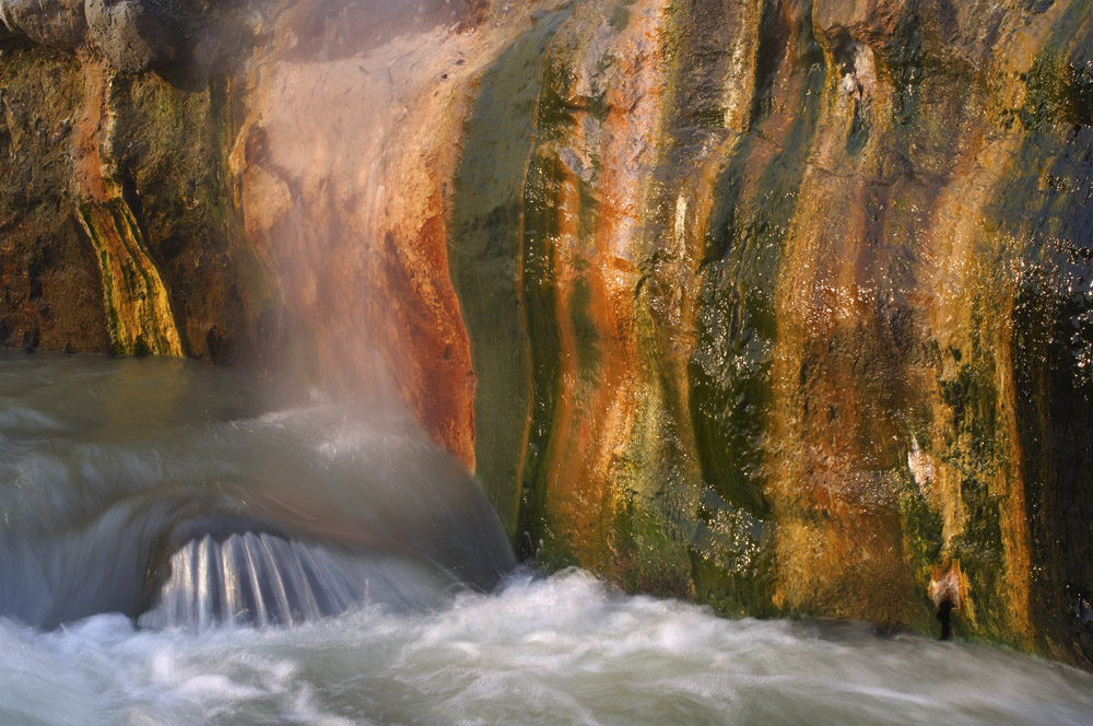 7/11. Светлост се прелама у дугиним бојама над водопадом који настаје из топлих извора, што представља погодну средину за раст разнобојних алги.