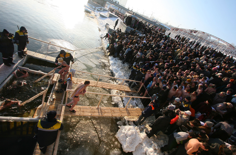 People climb down into the jordan on a small wooden ladder until they are half submerged, then they make the sign of the cross before fully submerging themselves in the water three times. (Volgograd region, Russia)