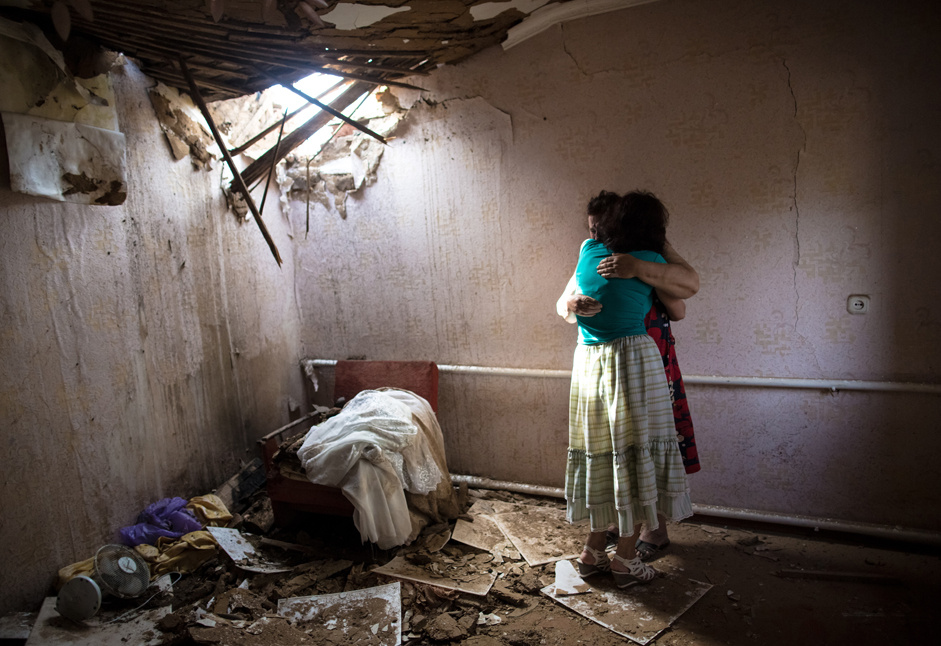 スラヴャンスク郊外で夜間に繰り広げられた砲撃により破壊された自宅にいる女性たち。 2014年