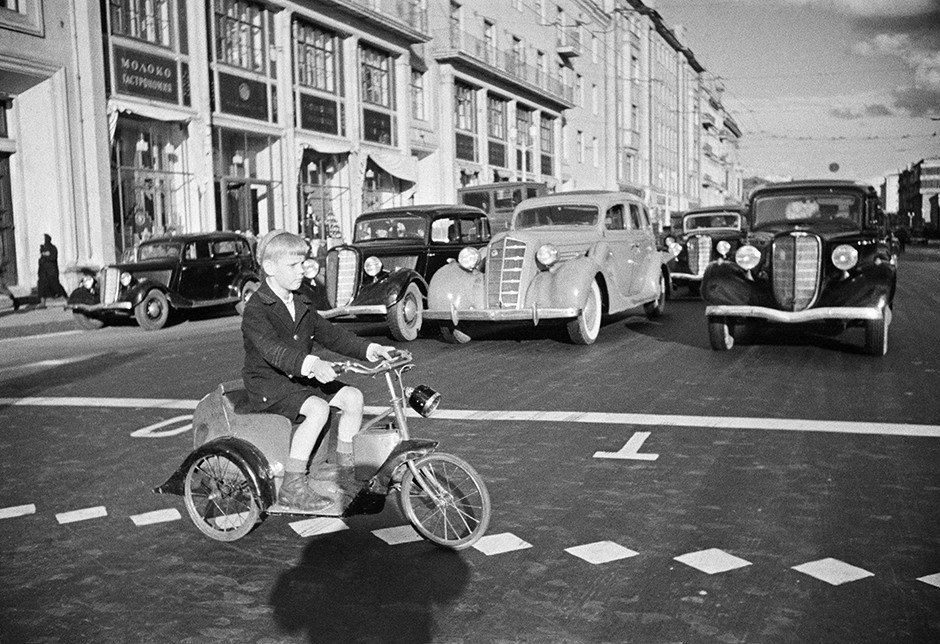 家族全員が彼を手伝い、写真を洗い、ガラスに並べ、グロスで仕上げ、出来上がった写真を切った。息子のアナトリーが修正をした。// ゴーリキー通りを自転車で渡る少年。モスクワ、1935年