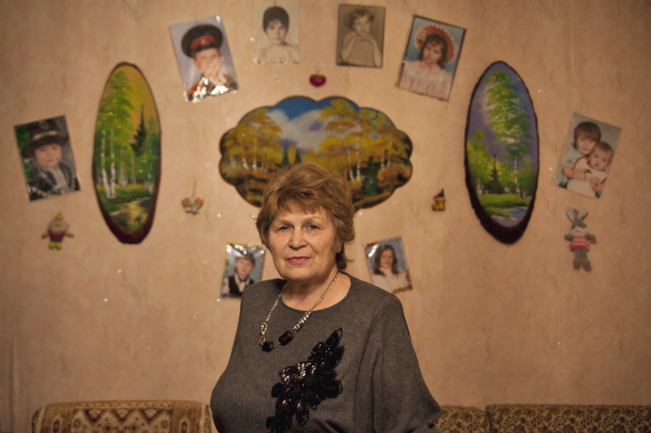 The wall that serves as a background for her portrait marvelously reflects the values of the rural teacher: Russian nature and photographs of her daughter and grandchildren.