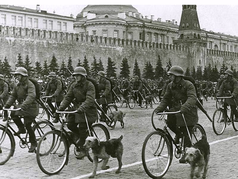 Platforms were set up near the main administrative building from where war veterans,  stakhanovites and the Communist Party heads gave speeches / Parade on Red Square, Moscow, May 1, 1938, Military dog handlers on bicycles