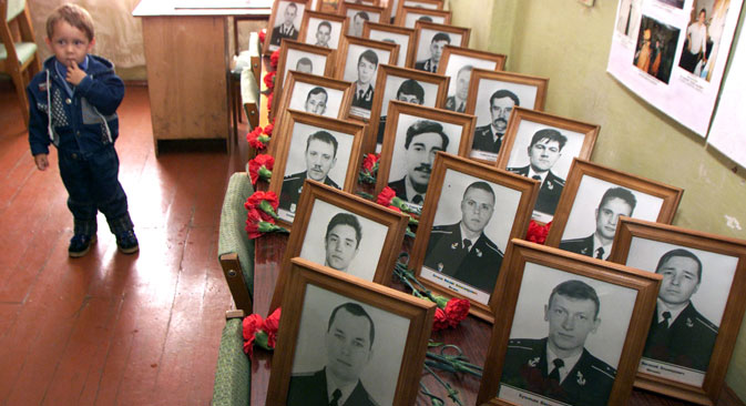 Русинче стои до портретите на жртвите од подморницата „Курск“ во нивната касарна во текот на меморијалната церемонија во руското арктичко пристаниште Видјаево, на 12 август, 2001. Семејствата на загинатите се собраа во Видјаево во неделата во сеќавање на 118 мажи кои исчезнаа една година претходно при потонувањето на руската атомска подморница „Курск“.