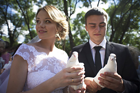 A newly wedded couple holds white doves in their hands at the unveiling ceremony of a monument dedicated to Saint Peter and Saint Fevronia, Orthodox patrons of fidelity, family and love. Source: Sergei Bobylev/TASS