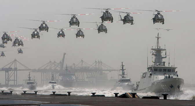 Indonesian air force helicopters fly over navy ships sailing in formation during the celebration of the 69th anniversary of the Indonesian armed forces.