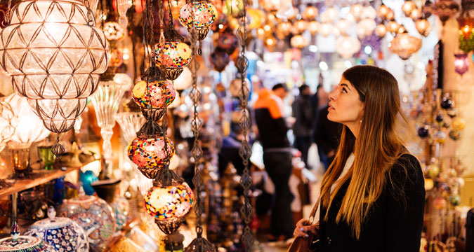 Young woman looking at lights on market stall, Istanbul, Turkey. 