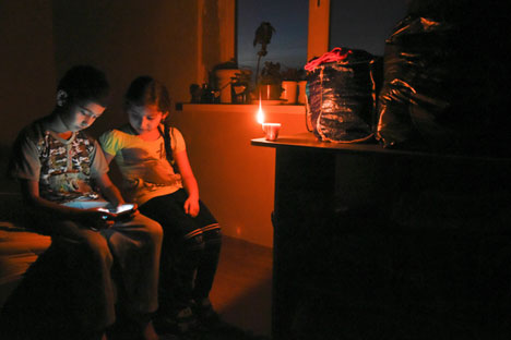 Ethnic Crimean Tatar children play on a cell phone by candlelight at their home in a village outside Simferopol after a power failure,  Crimea, Nov. 22, 2015.