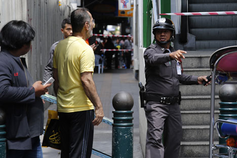A Royal Thai police officer tells locals and tourists to leave the scene after a suspicious package was detected near a skytrain (elevated light rail) station in downtown Bangkok, Thailand, 19 August 2015. 