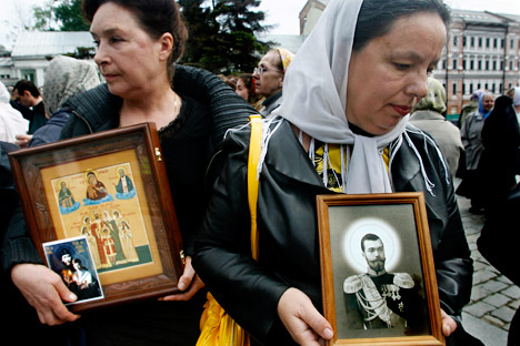 Des femmes tiennent des icônes représentant la famille des Romanov canonisée en 1981.