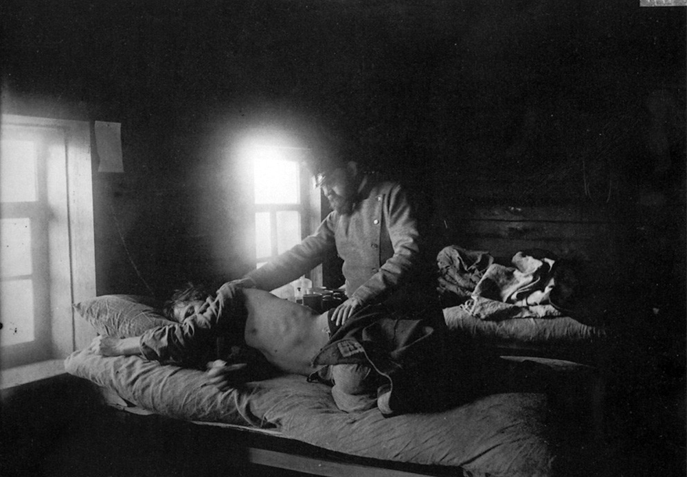 Un médecin examine un homme malade du typhus dans le village de Nakroussov.