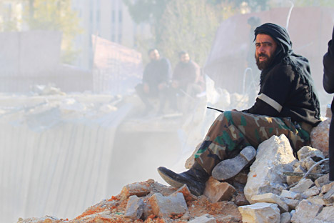A member of a local security force, in charge of policing the area sits on rubble while he oversees the search for survivors at a site hit yesterday by what activists said were airstrikes carried out by the Russian air force in Idlib city, Syria, December 21, 2015.