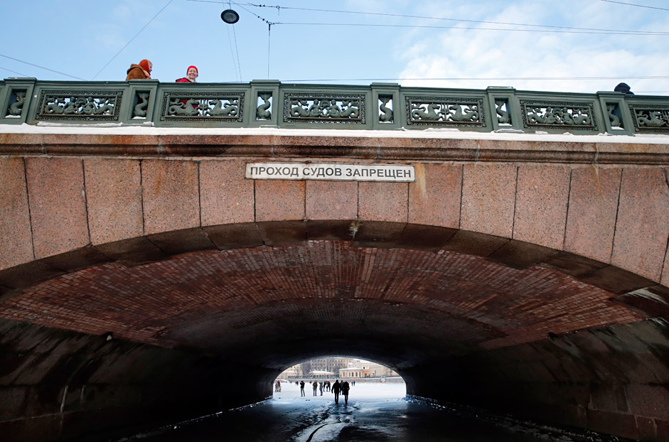 People pass the frozen Fontanka River under the Annichkov bridge in central St. Petersburg, Russia 24 January 2016. Temperatures dropped to minus 10 degree Celsius in the second capital of Russia, local media reports