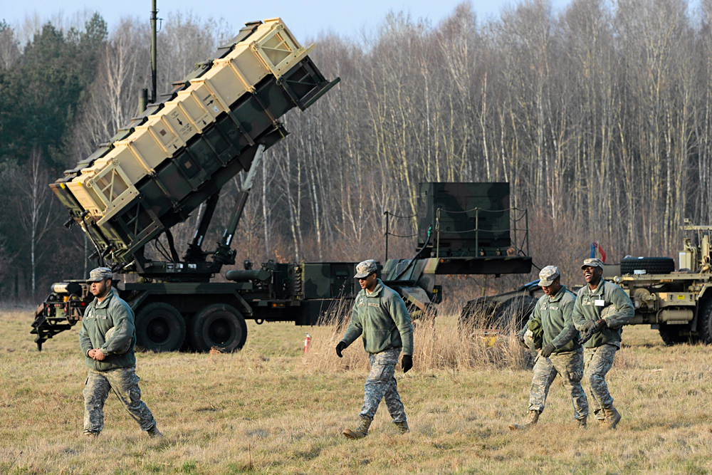 U.S. soldiers walk next to a Patriot missile defence battery during join exercises at the military grouds in Sochaczew, near Warsaw, March 21, 2015. 