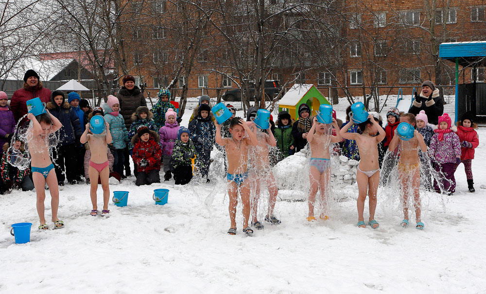 Деца ги набљудуваат своите соученици како се полеваат со студена вода, под надзор на фитнес тренерот Оксана Каботко (не е на сликата), како дел од програмата за здравје и фитнес во локалната градинка на температури под нулата, во Краснојарск, Сибир, Русија, 9 февруари, 2016 година. Програмата, која исто така вклучува и спортски тренинг и сауна, се практикува во градинката повеќе од 15 години. Децата почнуваат да се полеваат со студена вода на отворено по околу две до три години на обука и извршени медицински тестови; и градинката е единствената во регионот што ги користи овие вежби, според вработените. Градинката е единствената во Краснојарск каде што не беше регистриран ниту еден случај на заболување од грип, епидемија која го зафати регионот, соопштија локалните медиуми.