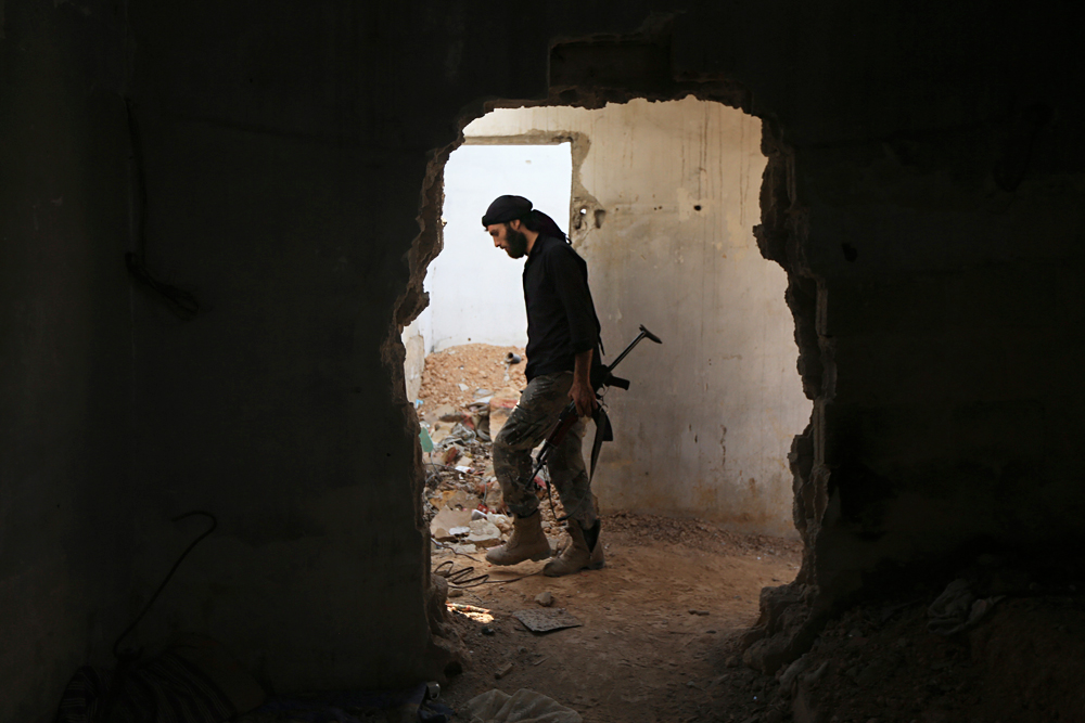 A fighter from the Free Syrian Army's Al Rahman legion carries his weapon as he moves inside a damaged building on the frontline against the forces of Syria's President Bashar al-Assad in Jobar, a suburb of Damascus, Syria, July 27, 2015.