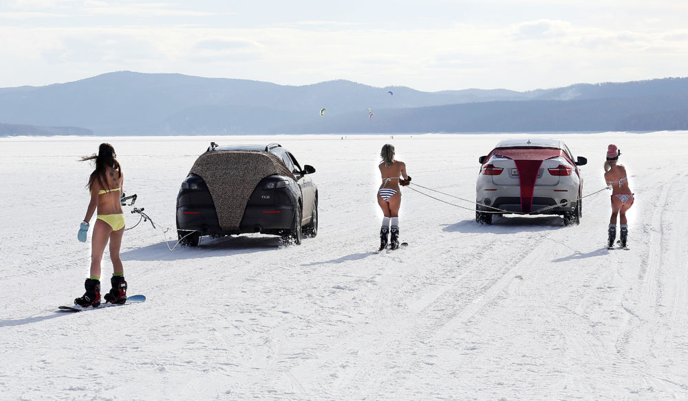 Bikini-clad women ski and snowboard as they are led by cars during a performance on the frozen Yenisei River outside Krasnoyarsk, Siberia, Russia