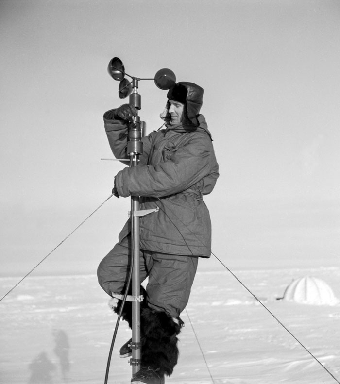 Les stations météo s’implantent même dans les endroits les plus reculés, y compris les îles de glaces de l’océan Arctique ou encore les plus hautes montagnes du monde. //1957. Un employé au pôle Nord travaillant au-dessus d’une station de recherche.