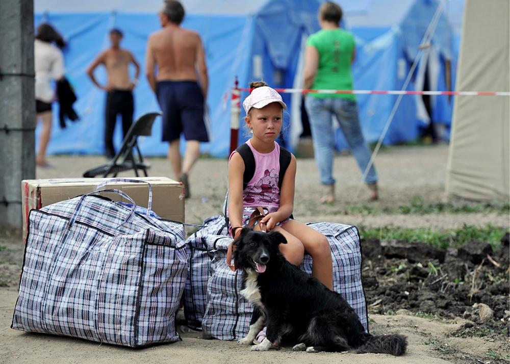A girl with a dog sits by her belongings in a camp for Ukrainian refugees near Gukovo crossing on the Russian-Ukrainian border, 2014