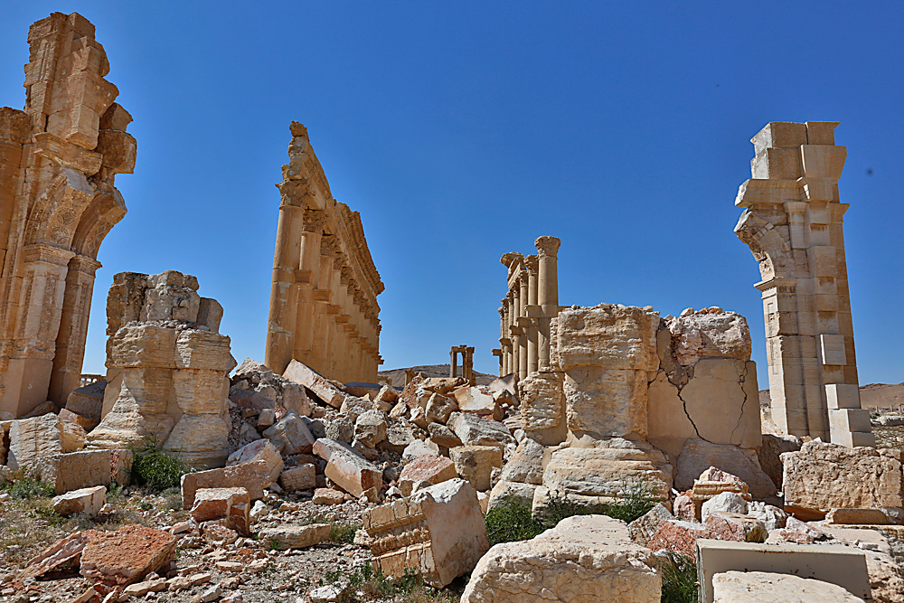 На тази снимка, направена на 1 април 2016 г., се виждат щетите, нанесени в древния град Пламира в централния град Хомс, Сирия. В петък Палмира бе разтърсена от взривове, а на хоризонта, зад величествените римски руини, се издигнаха кълба от черен дим, докато сирийските военни експерти внимателно детонираха стотици мини. Според тях взривните устройства са заложени от ислямистите, преди да избягат от града.