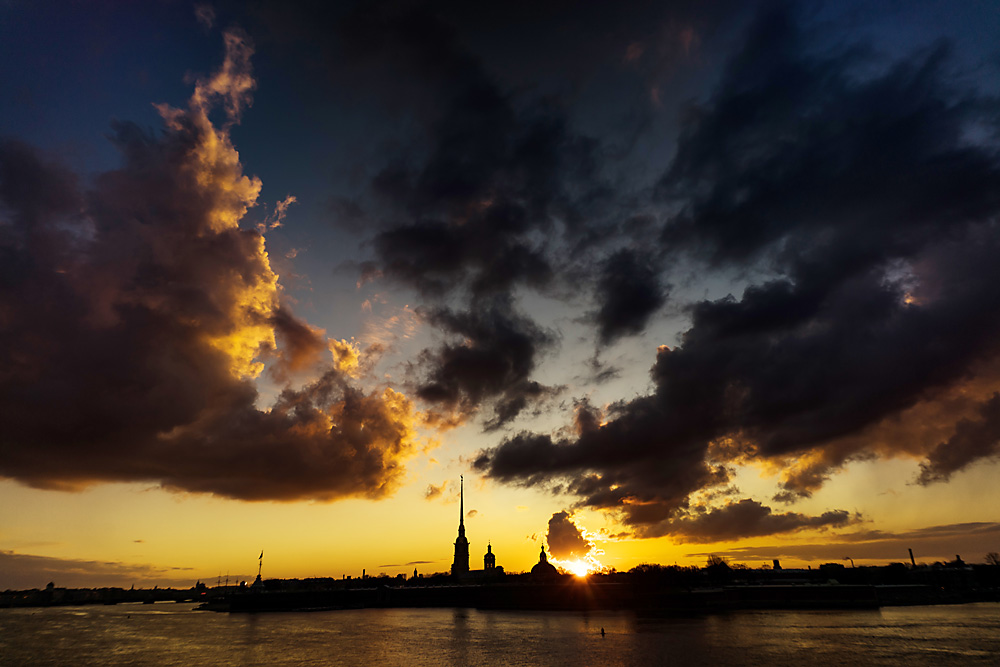 Sunset over an embankment of the Neva River. Background: Peter and Paul Cathedral and the Peter and Paul Fortress.