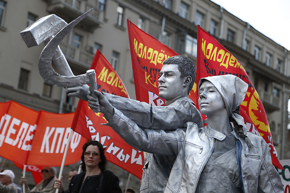 Членови и приврзаници на Комунистичката партија на РФ, со двајца од нив преправени во статуа со срп и чекан, дефилираат во текот на традиционалните првомајски демонстрации во Москва, Русија.