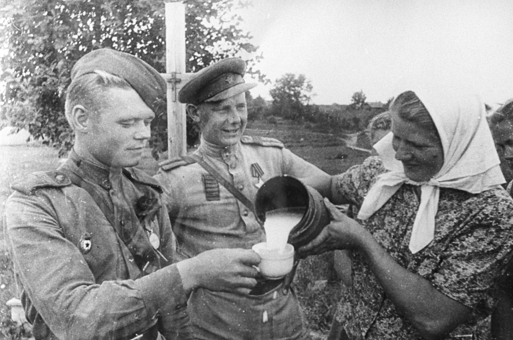 Жена им дава чаша млеко на војници на Црвената армија во Рига во 1944 година.