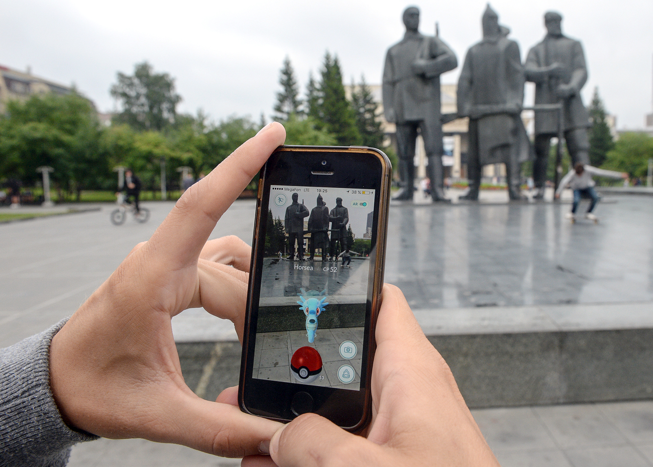 Pokémon Go, the mobile game from Nintendo, on their mobile phones in the park across the street from the Novosibirsk Opera