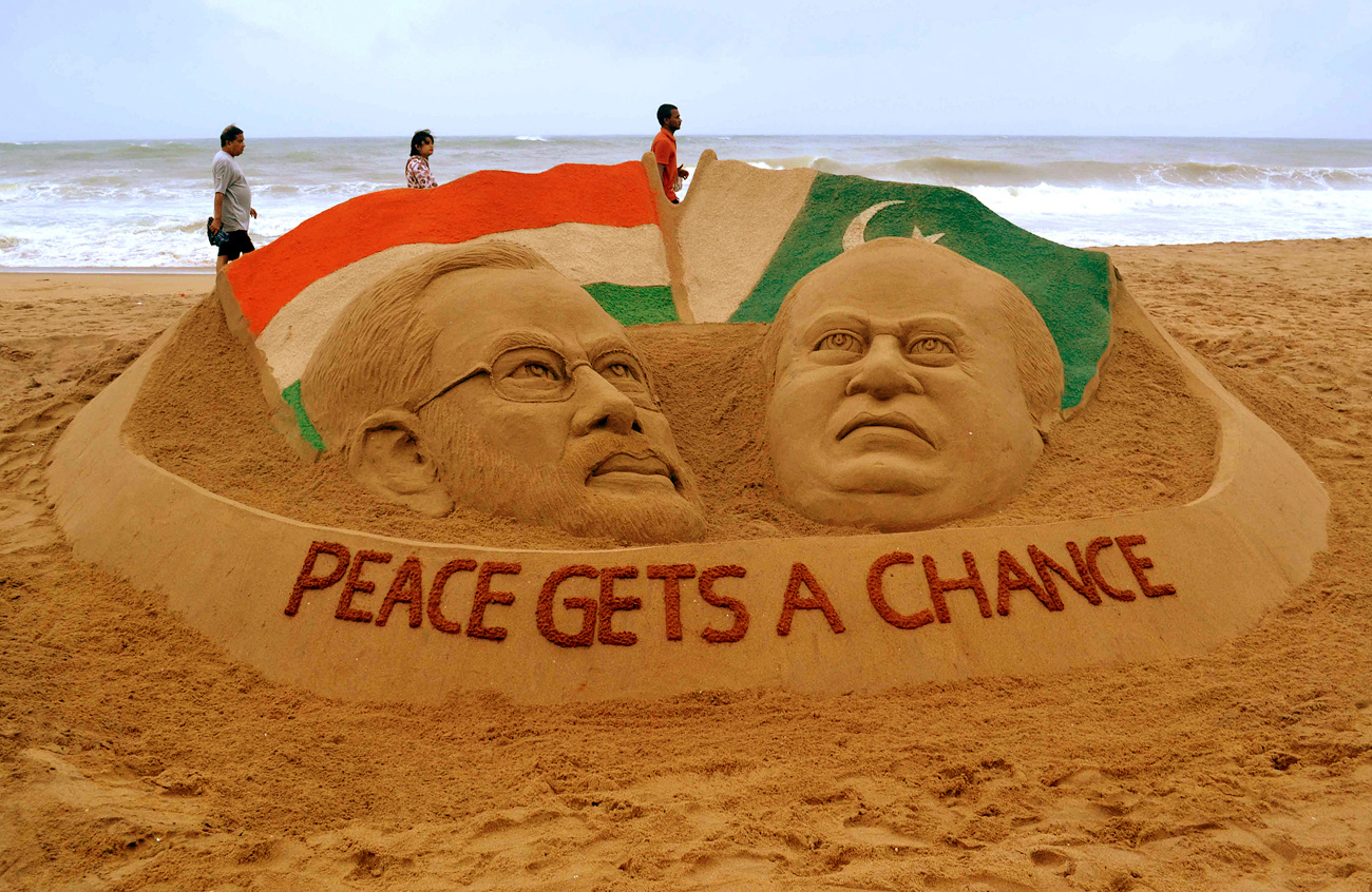 People stroll past a sand sculpture of Indian Prime Minister-designate Narendra Modi (L) and Pakistan's Prime Minister Nawaz Sharif, created by Indian sand artist Sudarshan Patnaik on a beach in Puri, in the eastern Indian state of Odisha, May 25, 2014. Pakistan has accepted an invitation to Sharif to attend the inauguration of Indian Prime Minister-designate Modi, an official said on Saturday. The Pakistani premier's attendance will be a first in the history of the nuclear-armed rivals, which have fought three wars since independence in 1947. 