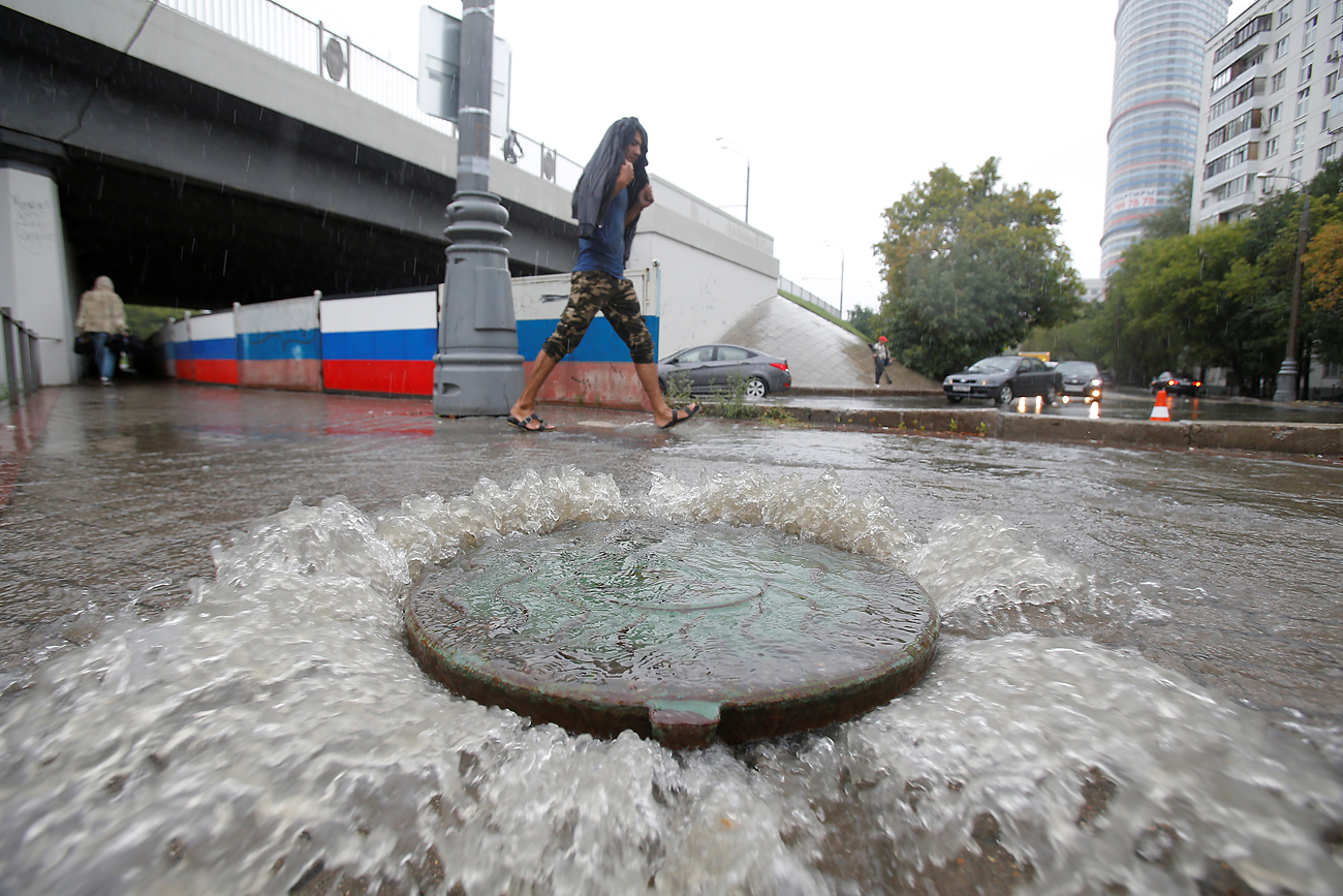 A man walks past a drain cover during heavy rains in Moscow, Russia, August 15, 2016.