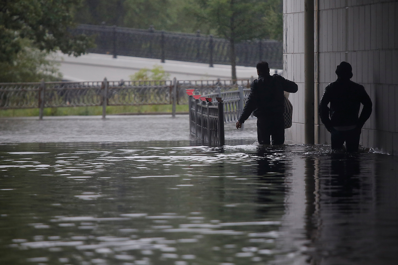 Men walk on a flooded road during heavy rains in Moscow, Russia, August 15, 2016. 