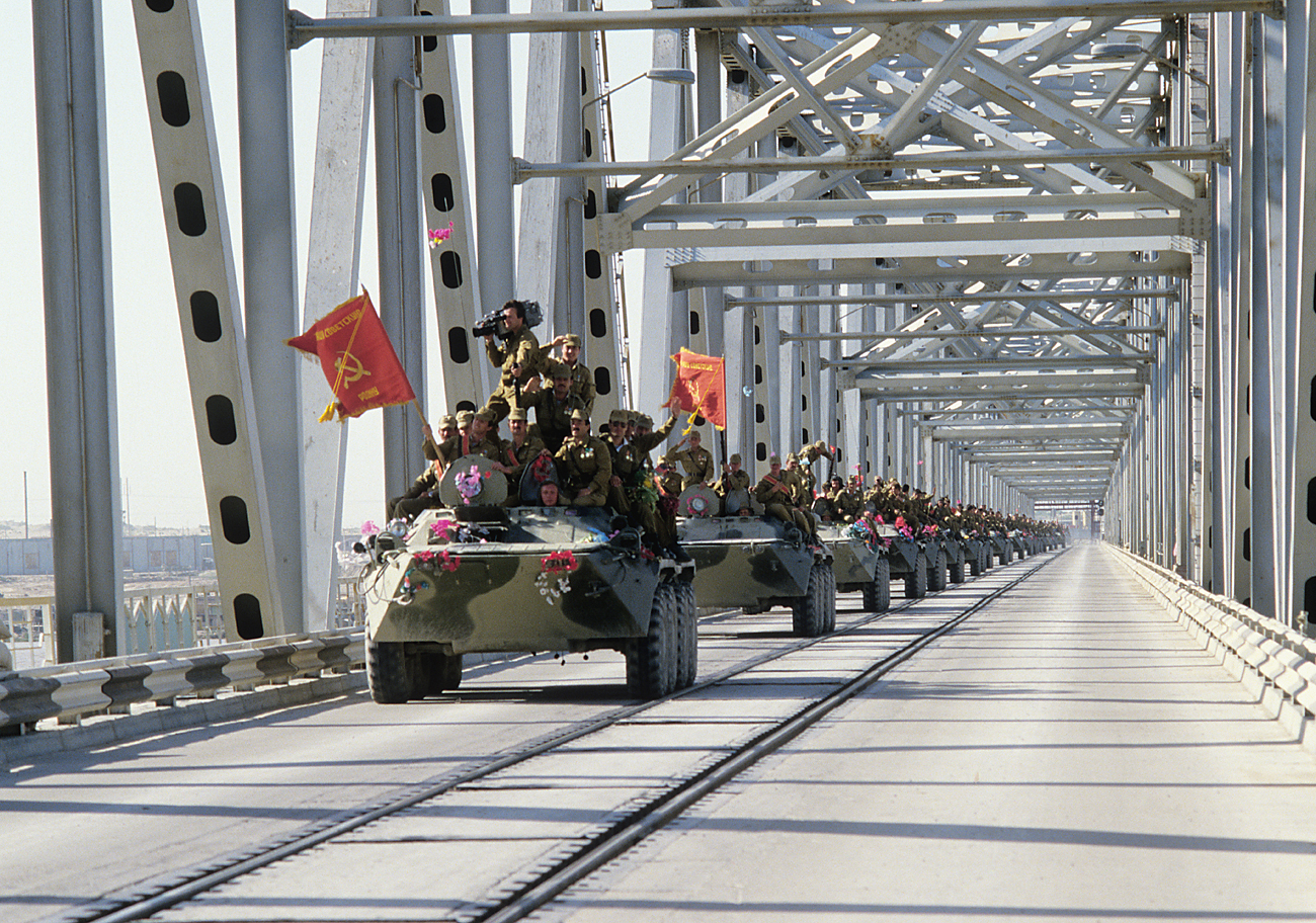 A column of armored vehicles crosses the Afghan-Soviet border on the Friendship Bridge over the Amu Darya River.