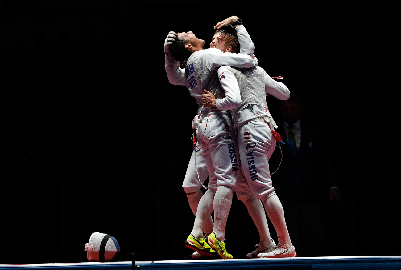 Timur Safin from Russia, celebrates with his teammate after defeating France during the Gold medal match in the men's team foil competition at the 2016 Summer Olympics in Rio de Janeiro, Brazil