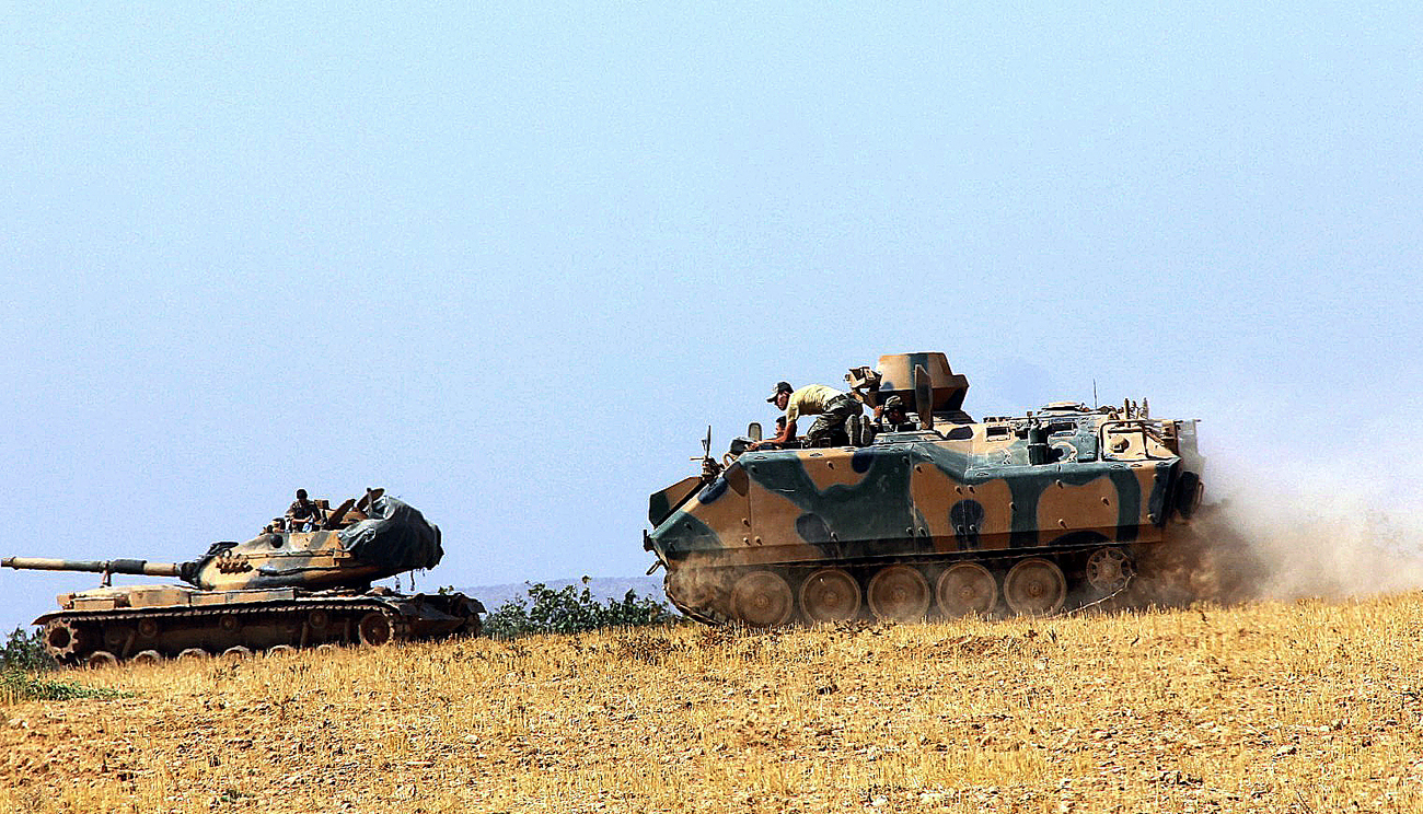 A Turkish army tank and an armored vehicle are stationed near the border with Syria, in Karkamis, Turkey.