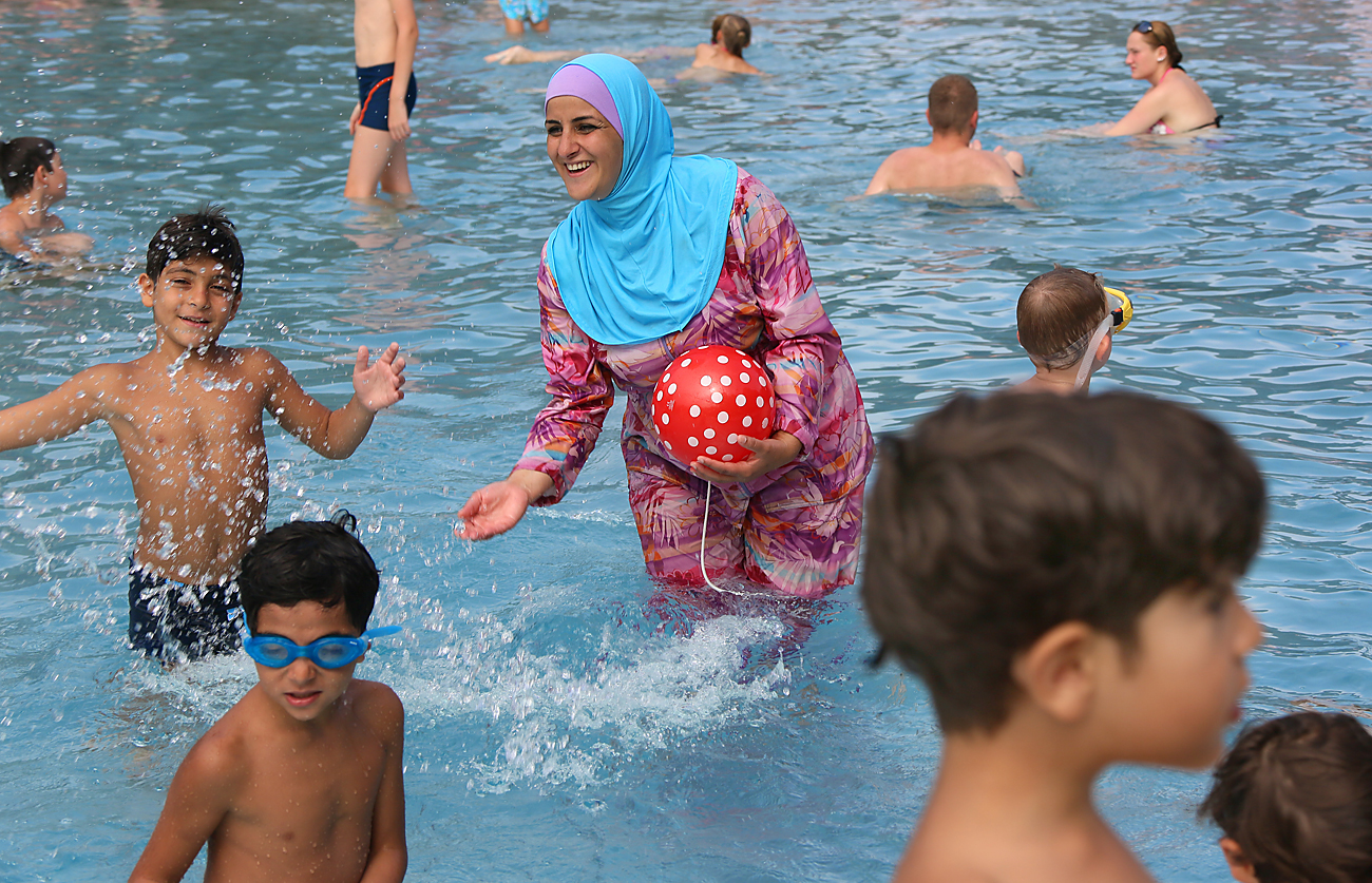 Il più delle volte le donne musulmane in Russia preferiscno nuotare con l'abbigliamento di tutti i giorni. In questa foto, una signora gioca con i propri figli in acqua. 