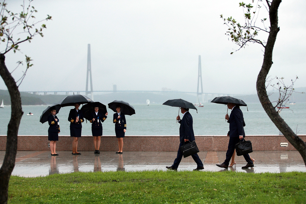 People hiding under umbrellas from the rain by the Ajax Bay ahead of the 2016 Eastern Economic Forum on Russky Island