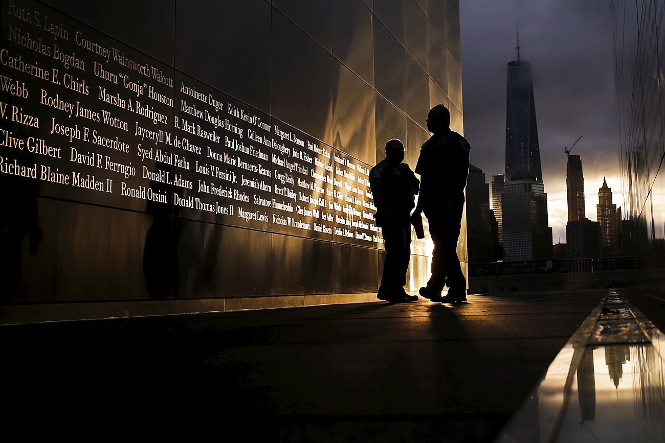 Orang-orang sedang membaca nama-nama korban tragedi 9/11 yang tertulis pada sebuah monumem peringatan menjelang matahari terbit di Liberty State Park, Jersey City, New Jersey, 11 September 2015. 