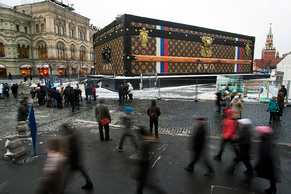 Turisti in obiskovalci hodijo mimo dvonadstropnega kovčka podjetja Louis Vuitton, ki so ga na Rdečem trgu postavili 27. novembra 2013. 9 metrov visoki in 30 metrov širok kovček so kmalu odstranili zaradi negativnih odzivov javnosti.