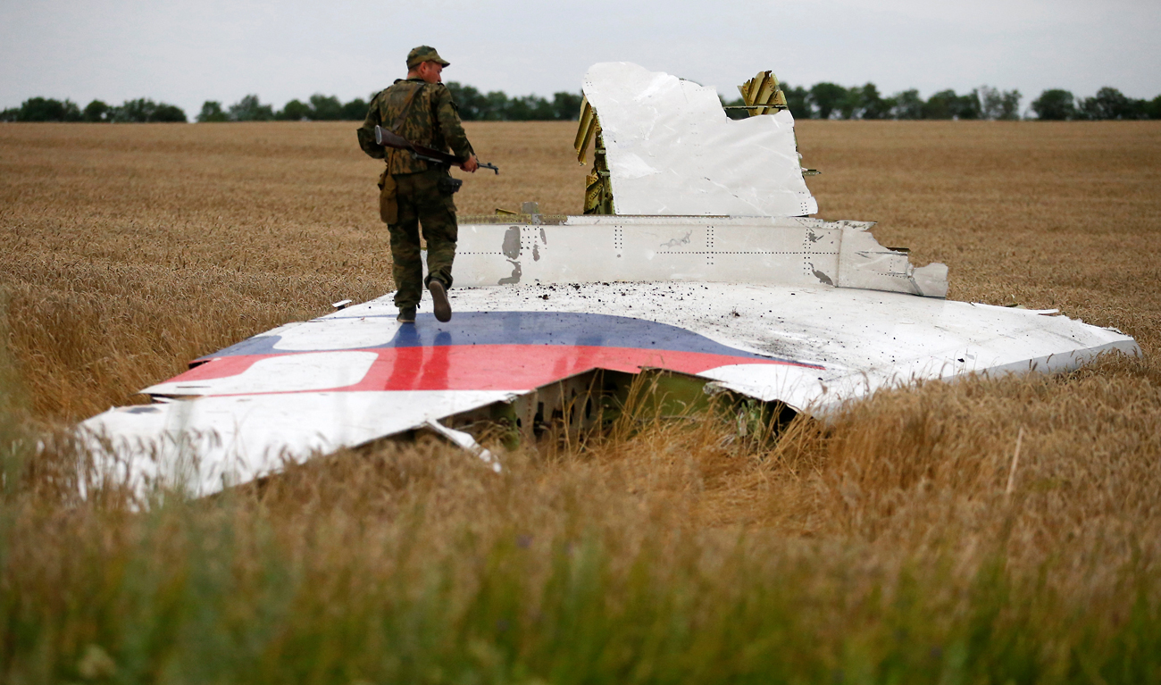 Un rebelle prorusse se tient sur un débris de l'épave de l'avion détruit, le 17 juillet 2014. 