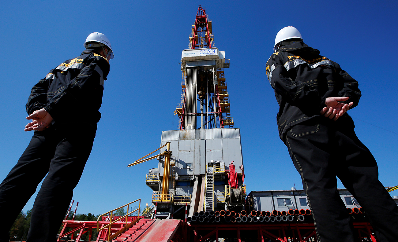 Workers look at a drilling rig at a well pad of the Rosneft-owned Prirazlomnoye oil field outside the West Siberian city of Nefteyugansk, Russia, on Aug.4, 2016. 