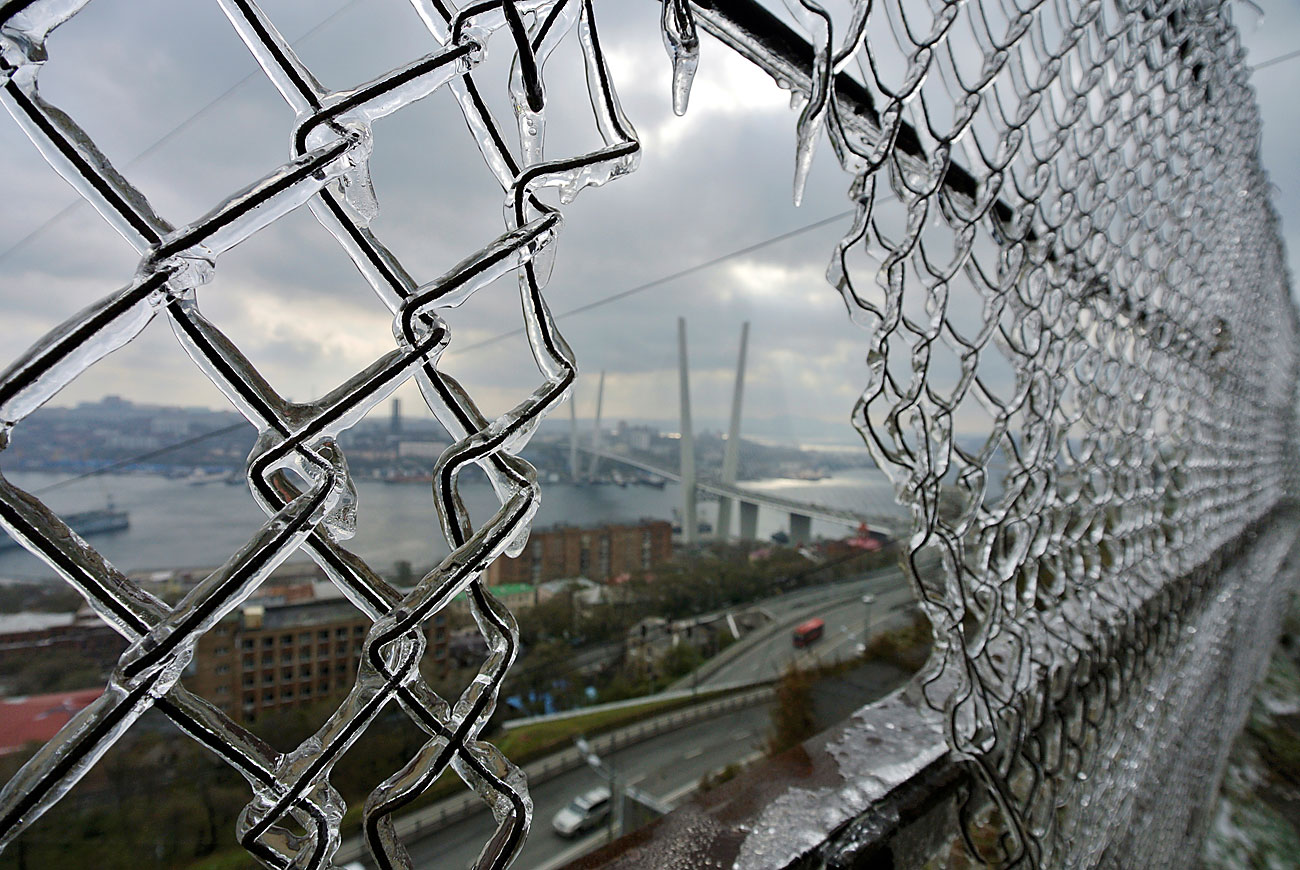 A bridge linking Russky Island with the mainland is seen through a fence covered with ice after freezing rain in the far eastern city of Vladivostok, Russia, October 22, 2016