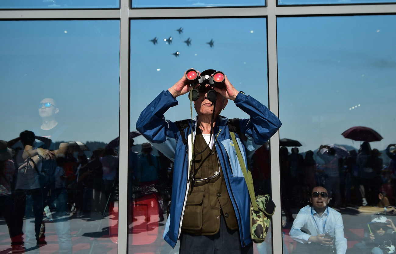 Visitors watch the Britain's Royal Air Force aerobatic display team performing in a formation flying during the 11th China International Aviation and Aerospace Exhibition at Zhuhai Airshow Center in Zhuhai, Guangdong Province of China on November 5, 2016.