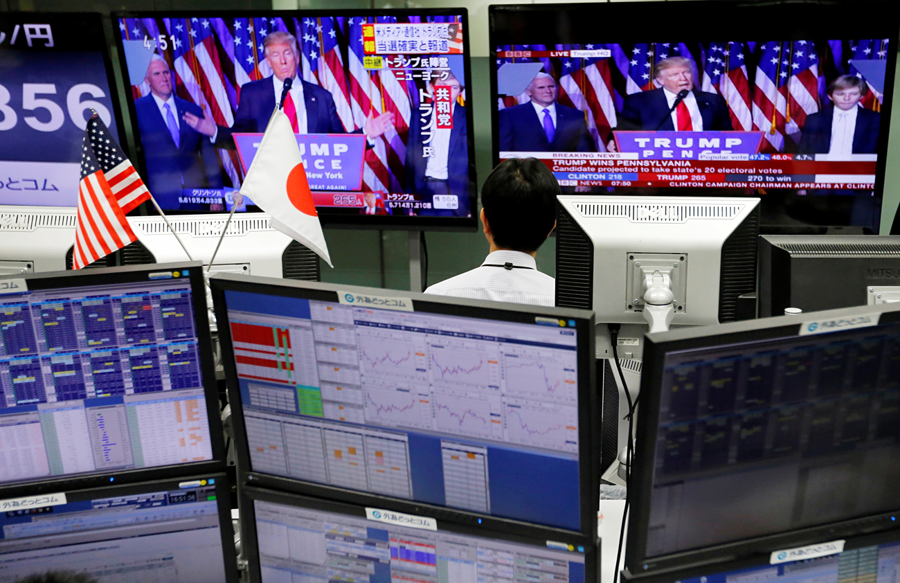An employee of a foreign exchange trading company looks at monitors showing U.S. President elect Donald Trump speaking on TV news in Tokyo, Japan, November 9, 2016. 