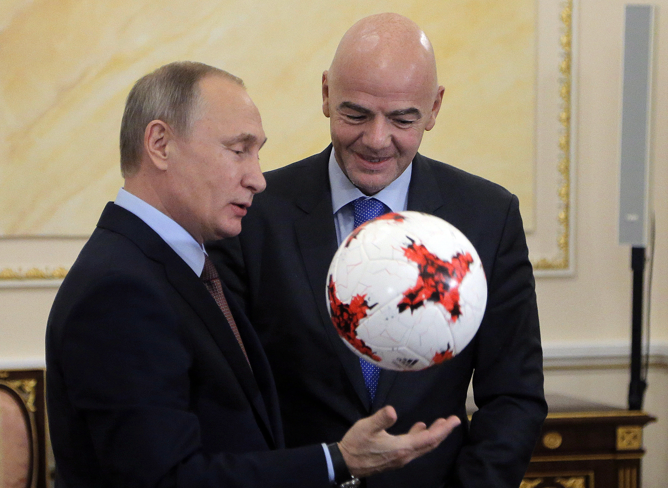 Russian President Vladimir Putin (L) receives an official match ball for the 2017 FIFA Confederations Cup from FIFA President Gianni Infantino during a meeting at the Kremlin in Moscow, Russia